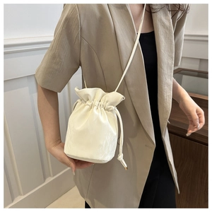 Chic cream white drawstring bucket bag shown with a beige blazer for a minimalist look