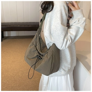 Detail view of olive green nylon tote bag featuring adjustable strap and side drawstring accent