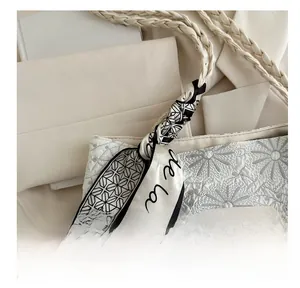 Detail of floral quilted shoulder bag with rope handle and geometric silk scarf decoration
