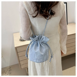 Close-up of light blue drawstring bucket bag with unique cloud texture and metal ends