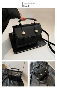 Dettaglio di una mini borsa quadrata in pelle nera con finiture dorate e manico