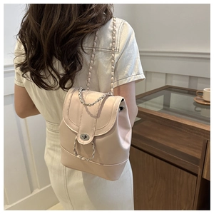 Detail shot of the beige mini backpack featuring a silver chain strap and twist-lock closure