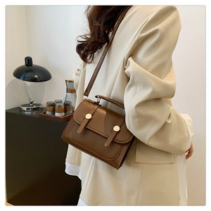Brown vintage leather crossbody bag shown on a model in a minimalist modern room