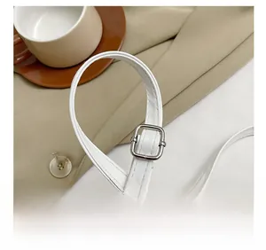 Detail of adjustable white leather shoulder strap with polished silver metal buckle