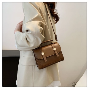 Detail view of a vintage caramel brown crossbody bag with double leather straps and gold buckles
