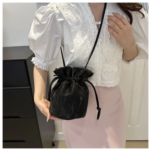 Women's black drawstring bucket bag with pleated satin texture and thin crossbody strap