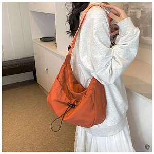 Detail of an orange nylon hobo tote bag with adjustable strap and drawstring toggle