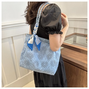 Close-up of light blue quilted tote bag with sunflower texture and geometric scarf detail
