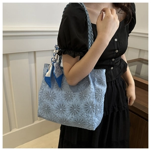 Detail of light blue quilted tote bag with daisy embroidery and floral silk scarf
