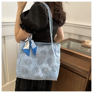 Quilted light blue daisy embroidered tote bag with silk scarf on model's shoulder