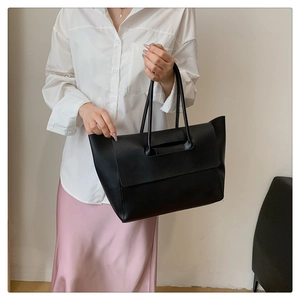 Detailed view of black large capacity wing tote bag being carried by a model