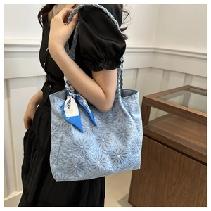Detail of light blue quilted tote with daisy patterns and woven handle and silk scarf
