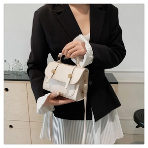 Detail of elegant cream handbag with gold circular twist locks and long shoulder strap