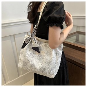 Detail of white canvas tote bag with daisy embroidery and decorative printed silk ribbon