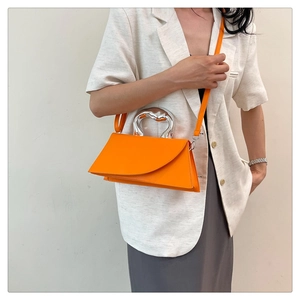 Close-up of bright orange crossbody bag with futuristic liquid silver metal handle