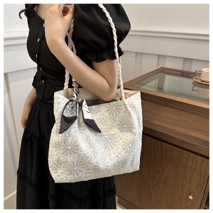 Close-up of white floral tote bag with woven strap and decorative geometric silk scarf