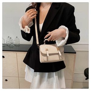 Close-up of a cream retro crossbody bag with golden buckle and leather strap details