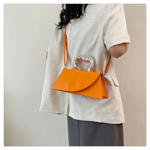 Détail d'un sac bandoulière orange vif avec poignée unique en métal argenté