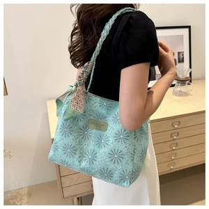 Detail of mint green tote bag featuring floral embroidery and woven shoulder strap