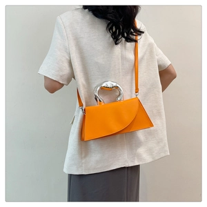 Sac à main trapèze orange chic avec poignée en métal argenté porté par un mannequin