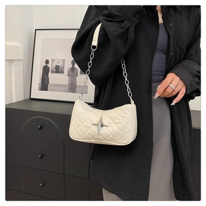 Close-up of quilted beige underarm bag featuring a silver star-shaped metal buckle detail