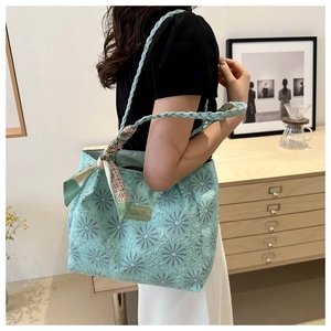 Detail of mint green tote bag with daisy jacquard pattern and floral scarf decoration