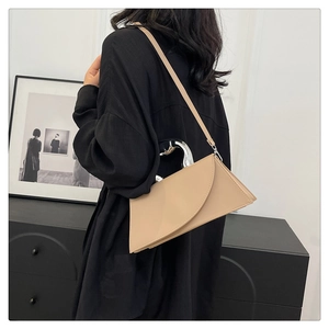 Détail du sac beige géométrique avec rabat asymétrique et poignée sculpturale en métal argenté