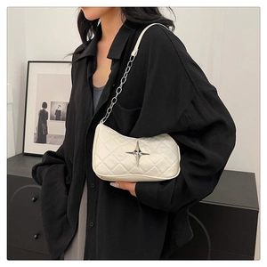 Quilted beige shoulder bag with silver star detail and chain strap worn by a model