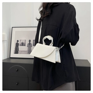 Détail du sac blanc structuré avec une poignée argentée en métal liquide et une bandoulière fine
