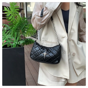 Detail of black quilted shoulder bag featuring silver star hardware and chain strap