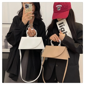 Détail d'un sac à main trapèze minimaliste avec poignée métallique ronde et cuir lisse élégant