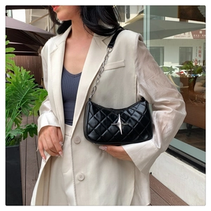 Close-up of black quilted shoulder bag with silver star logo and chain leather strap