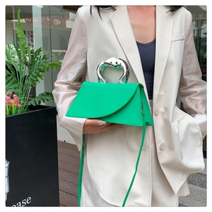 Sac à main asymétrique vert pomme chic avec poignée argentée sur un blazer beige