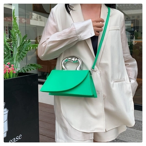 Close-up of vibrant green leather handbag with a silver heart-shaped metal top handle