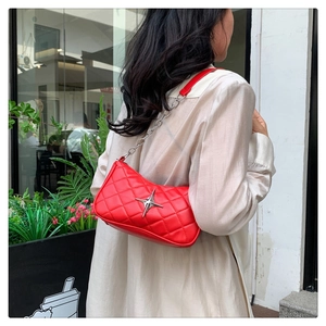 Macro detail of red quilted shoulder bag featuring silver star metal buckle and chain strap