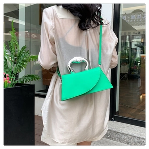 Détail d'un sac à main géométrique vert fluo avec poignée cœur argentée et fine bandoulière