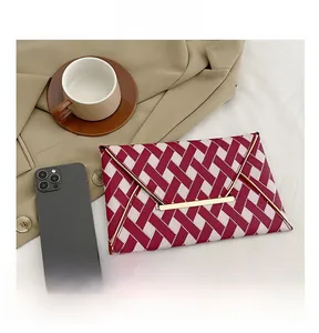 Detail of red and pink woven envelope clutch with gold metal bar and phone size comparison