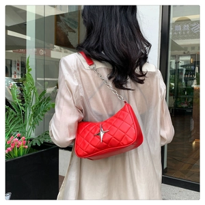 Close-up of red quilted shoulder bag with silver star clasp and metal chain strap