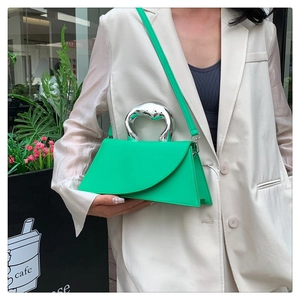 Détail du sac à main en cuir vert vif avec poignée métallique argentée et fine bandoulière