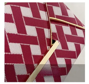 Detail of red and white lattice pattern on envelope bag with gold metal trim
