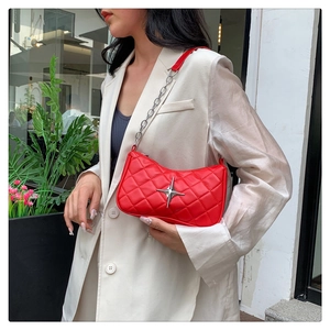 Detail of red quilted faux leather bag featuring a silver star and chain strap