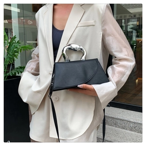 Détail du sac à main noir minimaliste avec poignée sculpturale en métal argenté