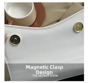 Détail du sac à main en cuir blanc montrant son fermoir magnétique doré et ses coutures