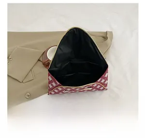 Detail view of red and white plaid envelope clutch with multi-compartment interior