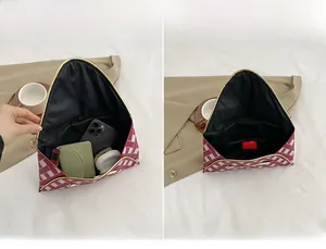 Detail of red and white woven envelope clutch showing interior storage for phone and makeup