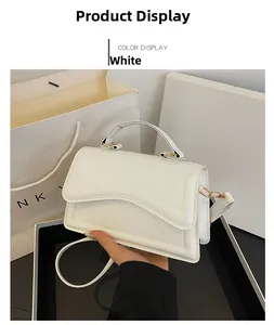 Détail du sac blanc en similicuir avec rabat ondulé et poignée en métal doré
