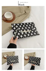 Detail of a black and white twill envelope clutch bag with gold metallic bar decoration