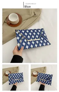 Detail view of a blue and white woven envelope clutch with gold metal trim and black strap