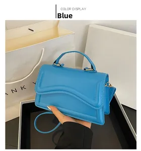 Détail du sac bleu en similicuir avec rabat ondulé et finitions dorées chic