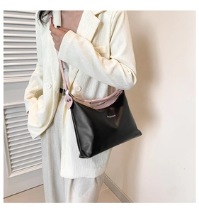 Close-up of black tote bag with pink strap and white Fashion logo worn with cream blazer